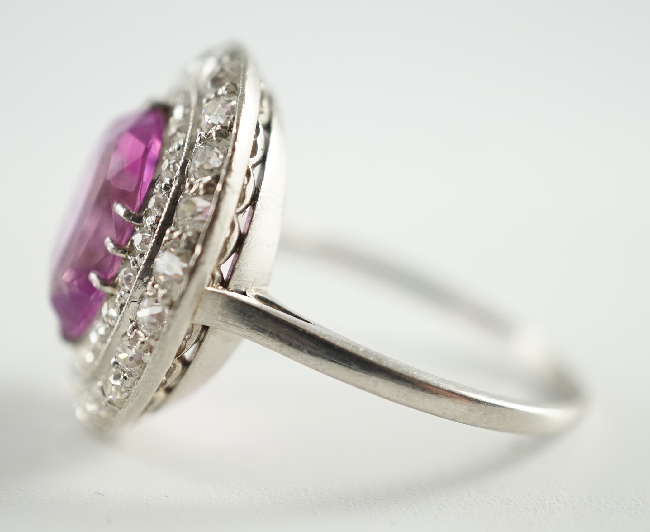 An early 20th century platinum, oval cut purple-pink sapphire and round cut diamond cluster set dress ring